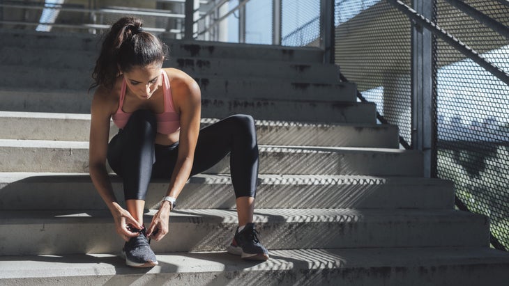 Beautiful Caucasian Sportswoman Tying Laces on Running Sneakers, a Close Up