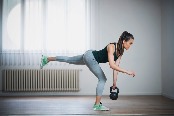 Young woman doing single-leg kettlebell deadlift, a great glute activation and injury prevention exercise
