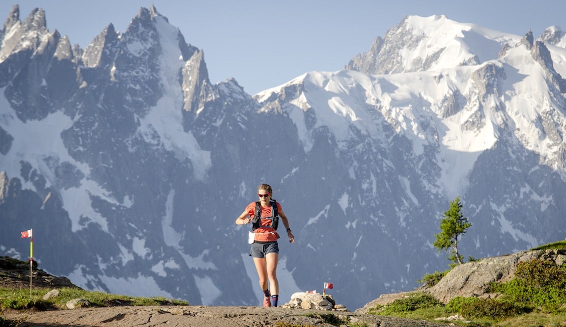 Trail runner cresting hill with Alps in the background