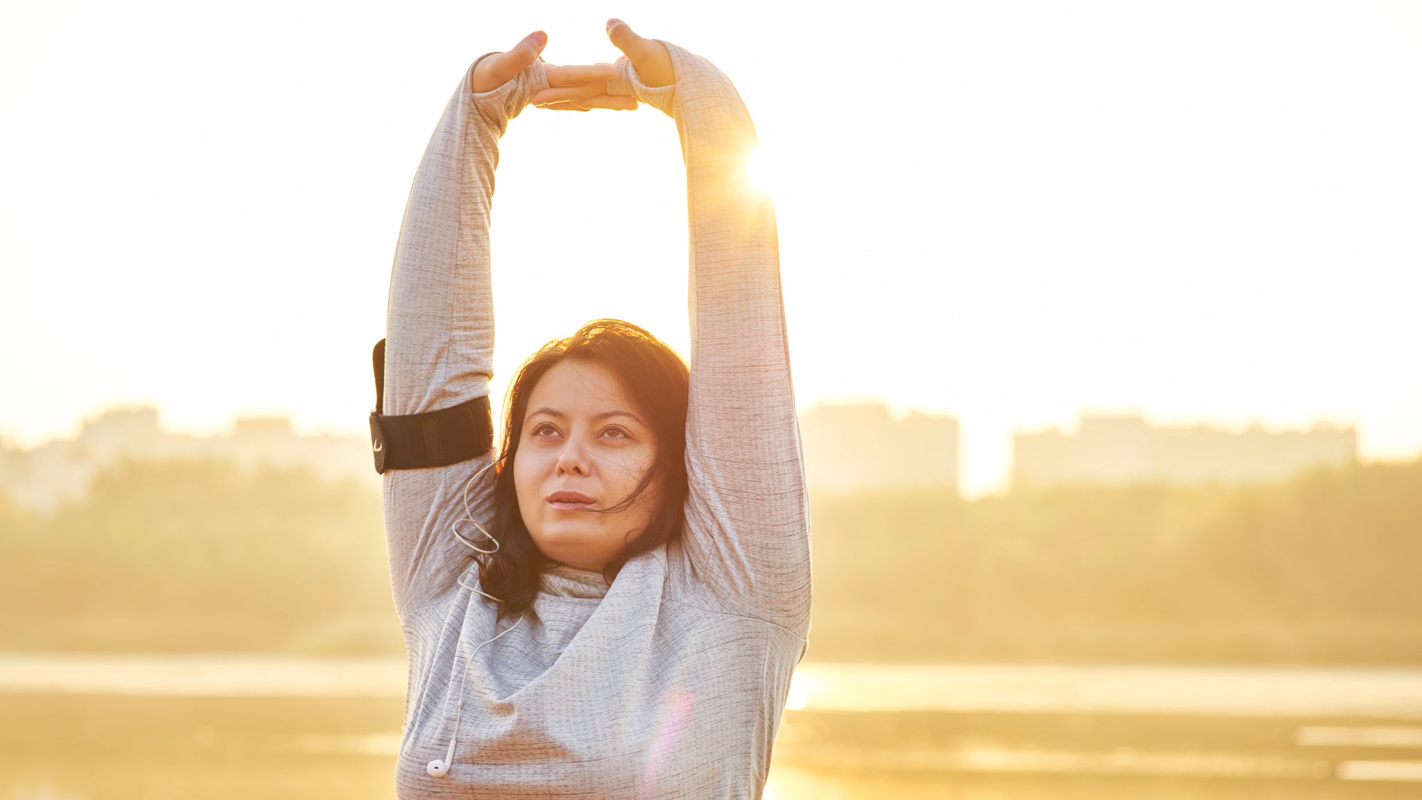 Woman stretching in the morning sun outside of a city