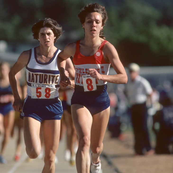 Two women run on a track toward the camera