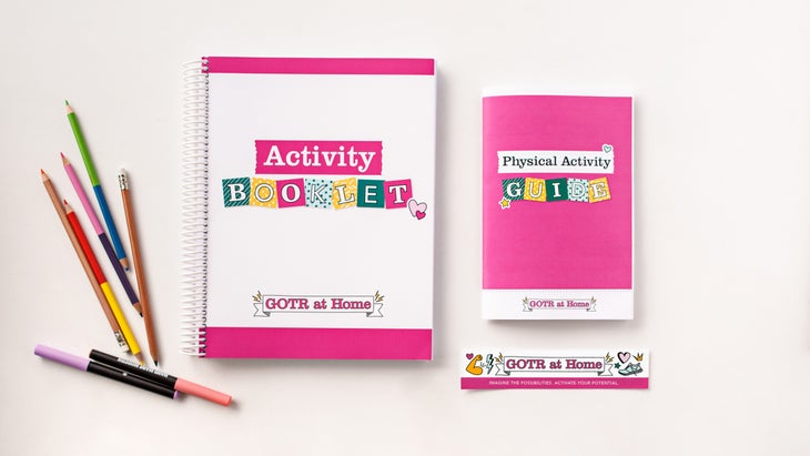 Two pink-and-white booklets from above surrounded by colored pencils and a GOTR sticker