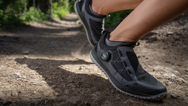 Close-up of black shoes running on a wooded trail