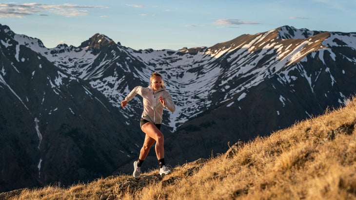 A woman runs up a mountainous trail