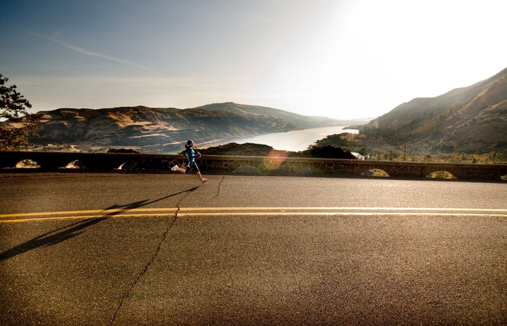 Woman jogging a fartlek workout on highway in landscape
