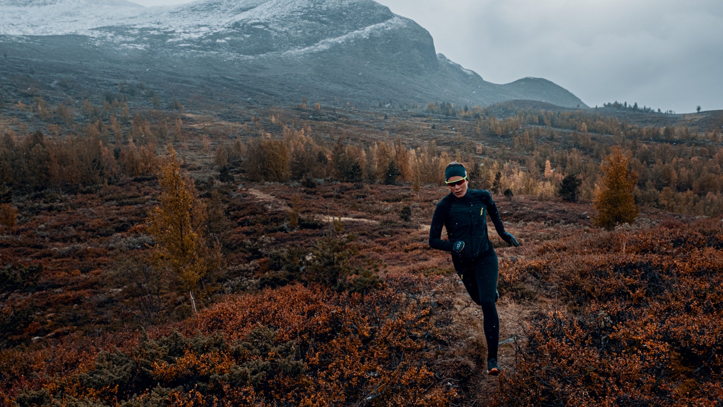 Woman running on trail below mountains
