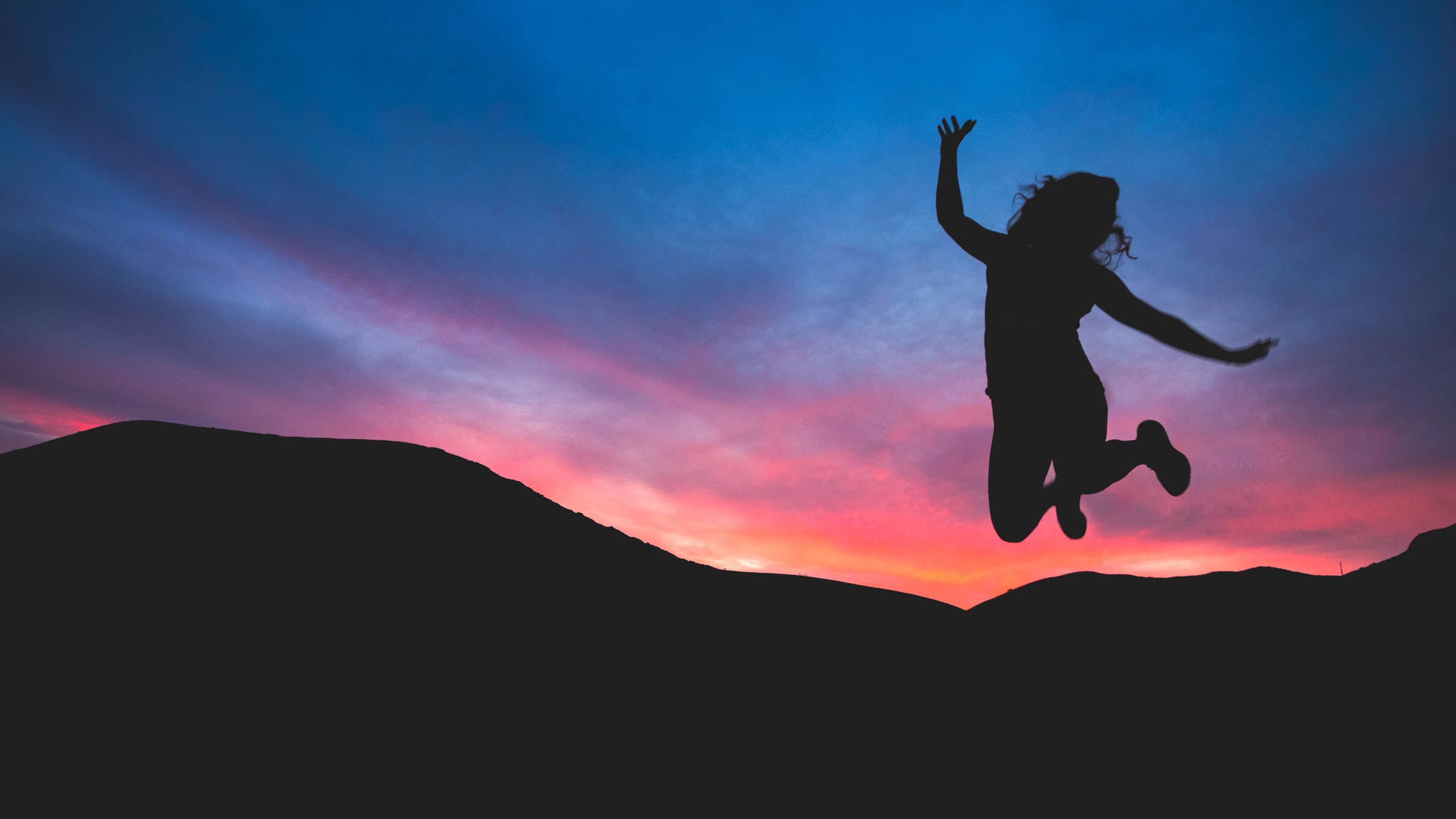 Silhouette of a woman jumping at sunset