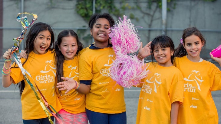 Girls stand in a line wearing yellow Girls on the Run shirts.