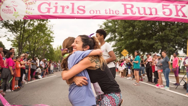 Girls on the Run mentor hugs participant at 5k finish line.