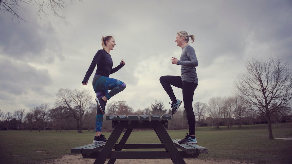 Full length side view of women doing step ups on picnic bench