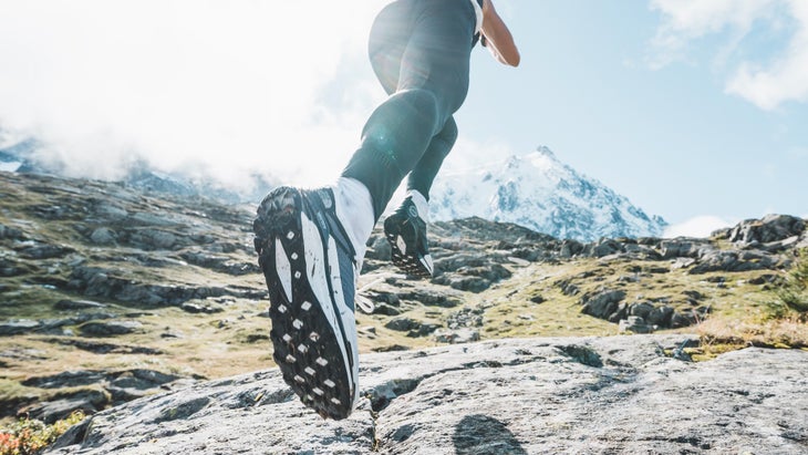 Close-up on Vectic trailrunning shoe on woman running uphill in the mountains.