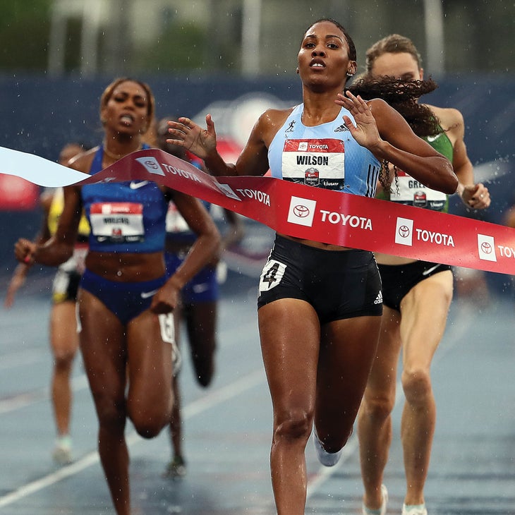 Ajee' Wilson running through finish line red tape