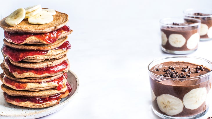 A tall stack of green banana pancake sandwiches next to glass bowls of chocolate chia seed pudding, two gut health recipes