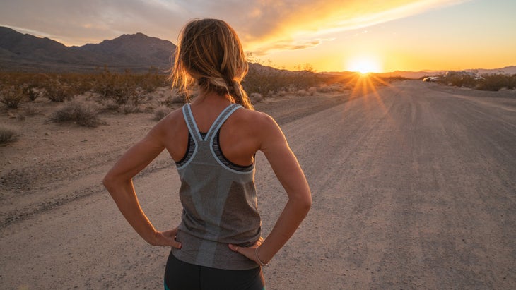 Woman at sunset on the end of the road after running.