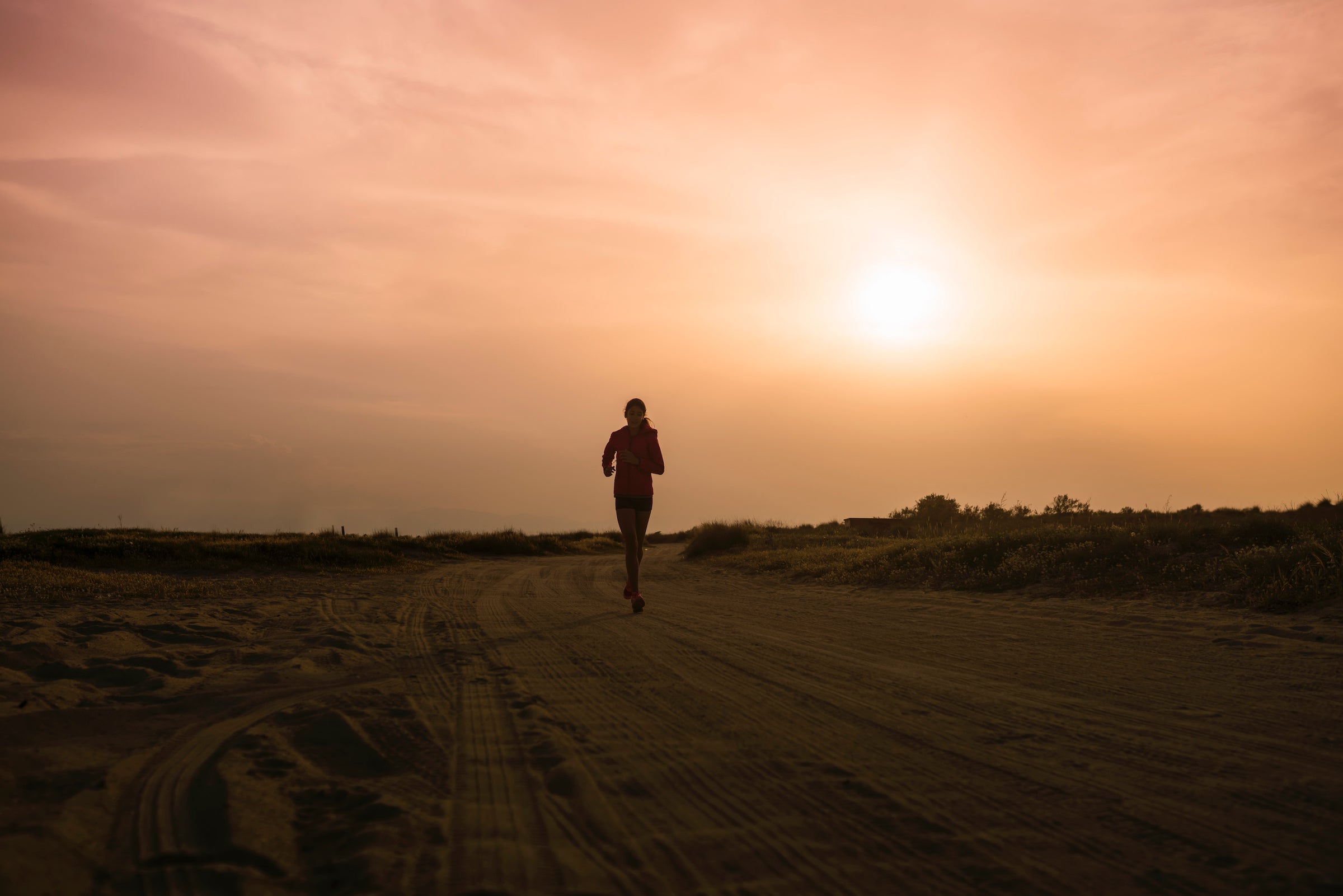 silhouette of woman jogging at sunset in low light