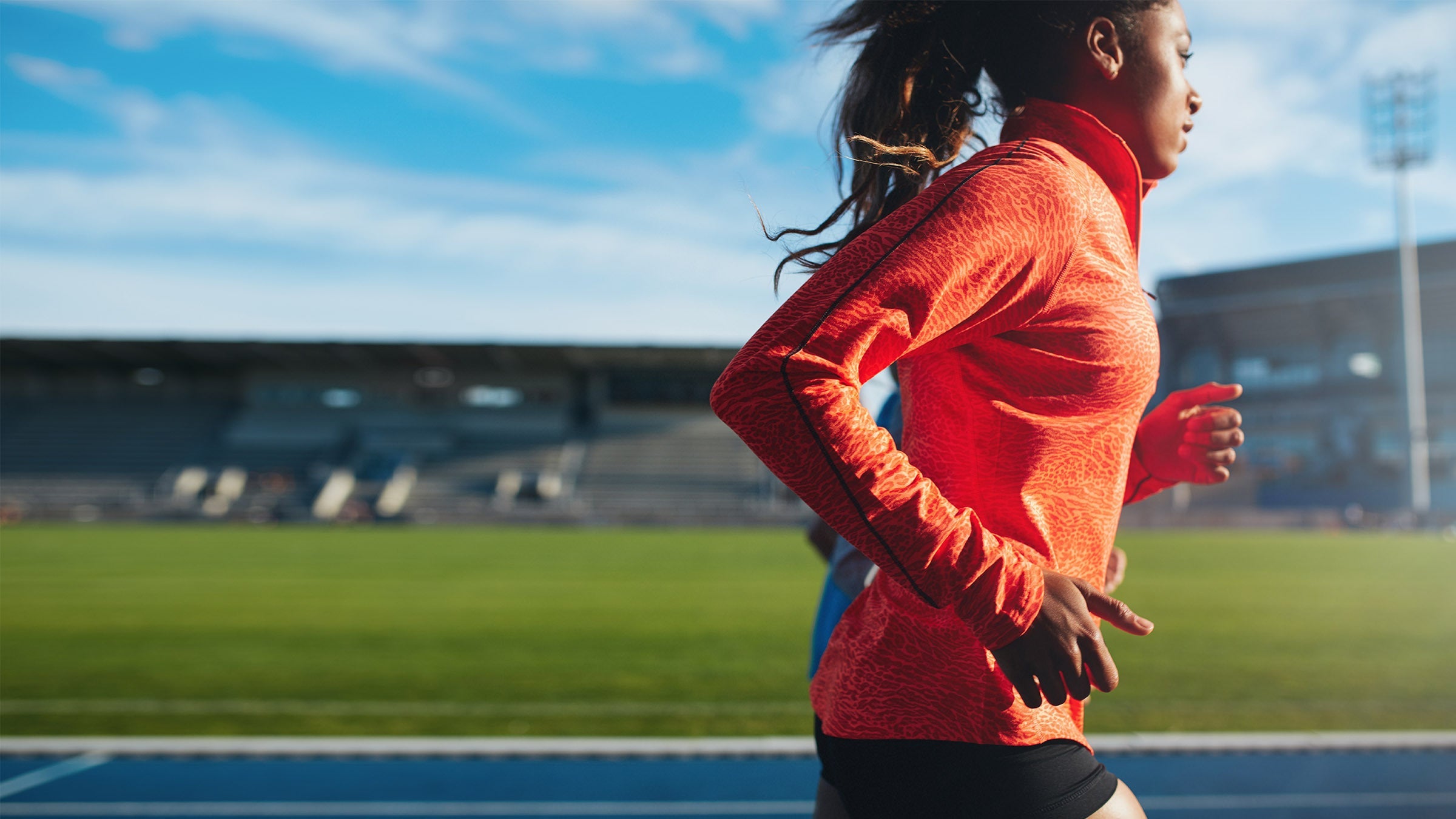 Woman in orange animal-print longsleeve running on track