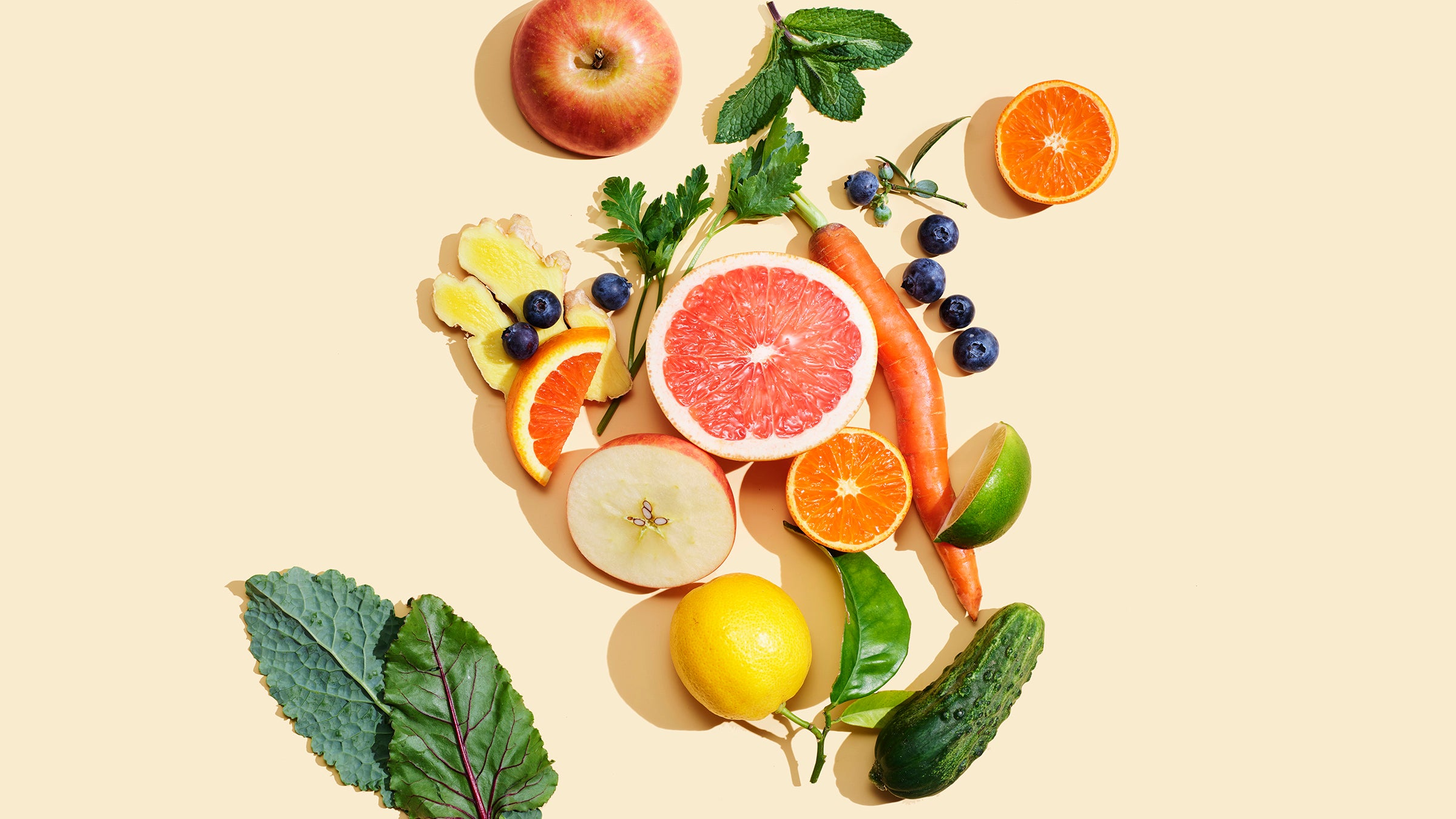 fruit and vegetables, which are foods that help lower stress and anxiety, arranged overhead on peach surface