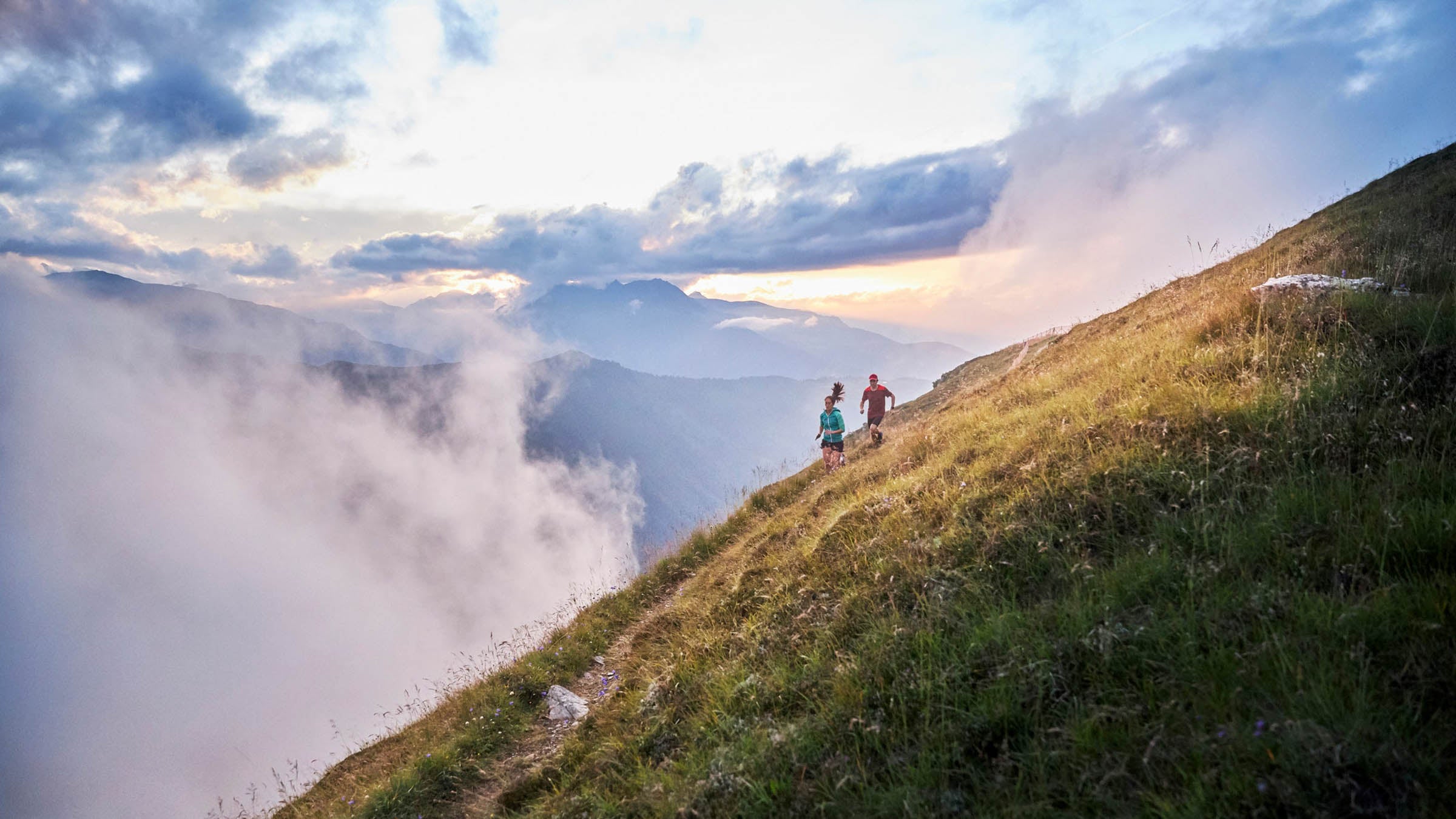 Man and woman running uphill in the mountains
