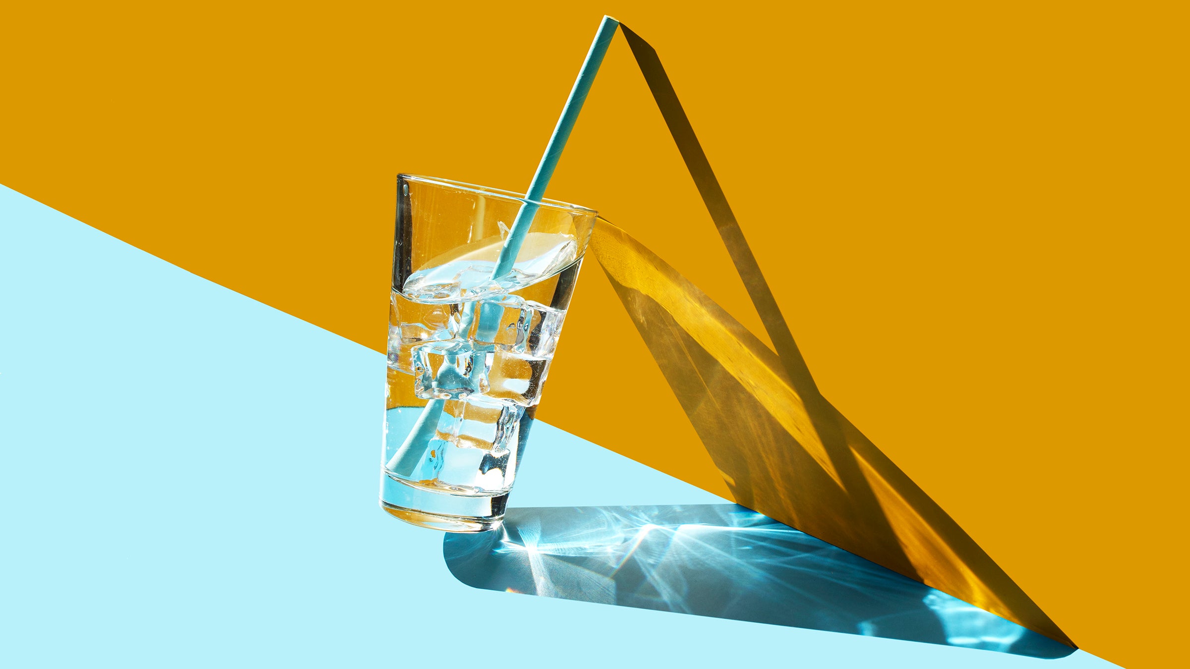 Glass of ice water on blue and yellow background