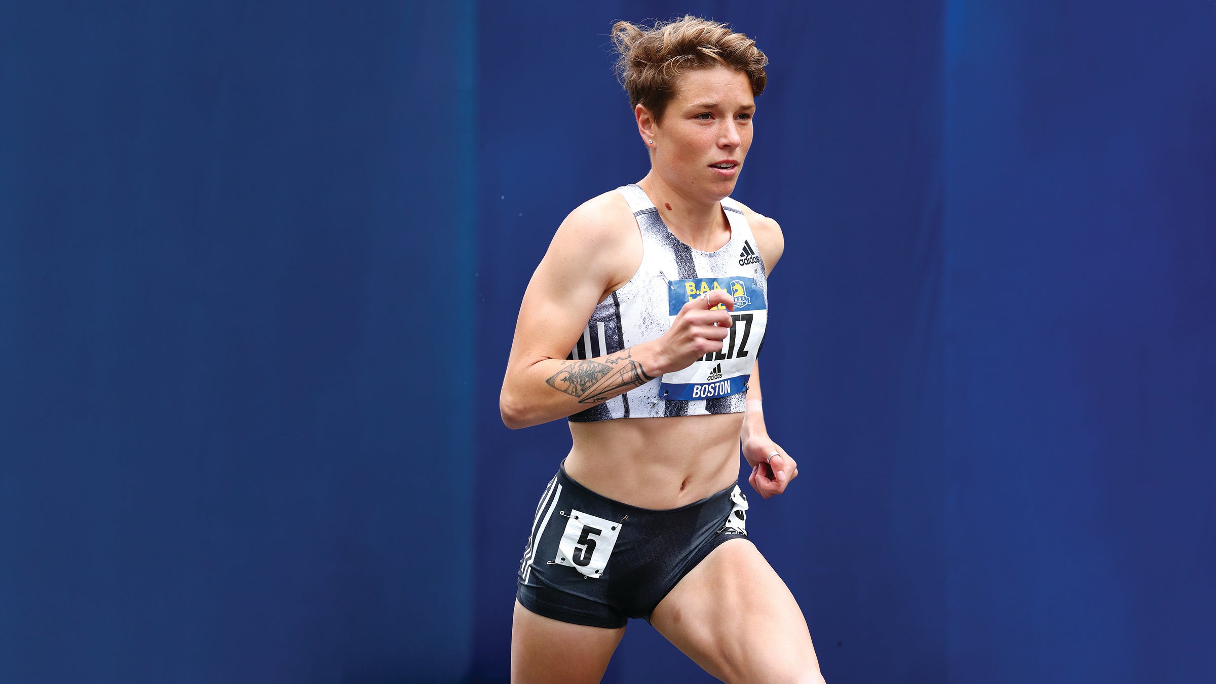 Nikki Hiltz running on a blue background