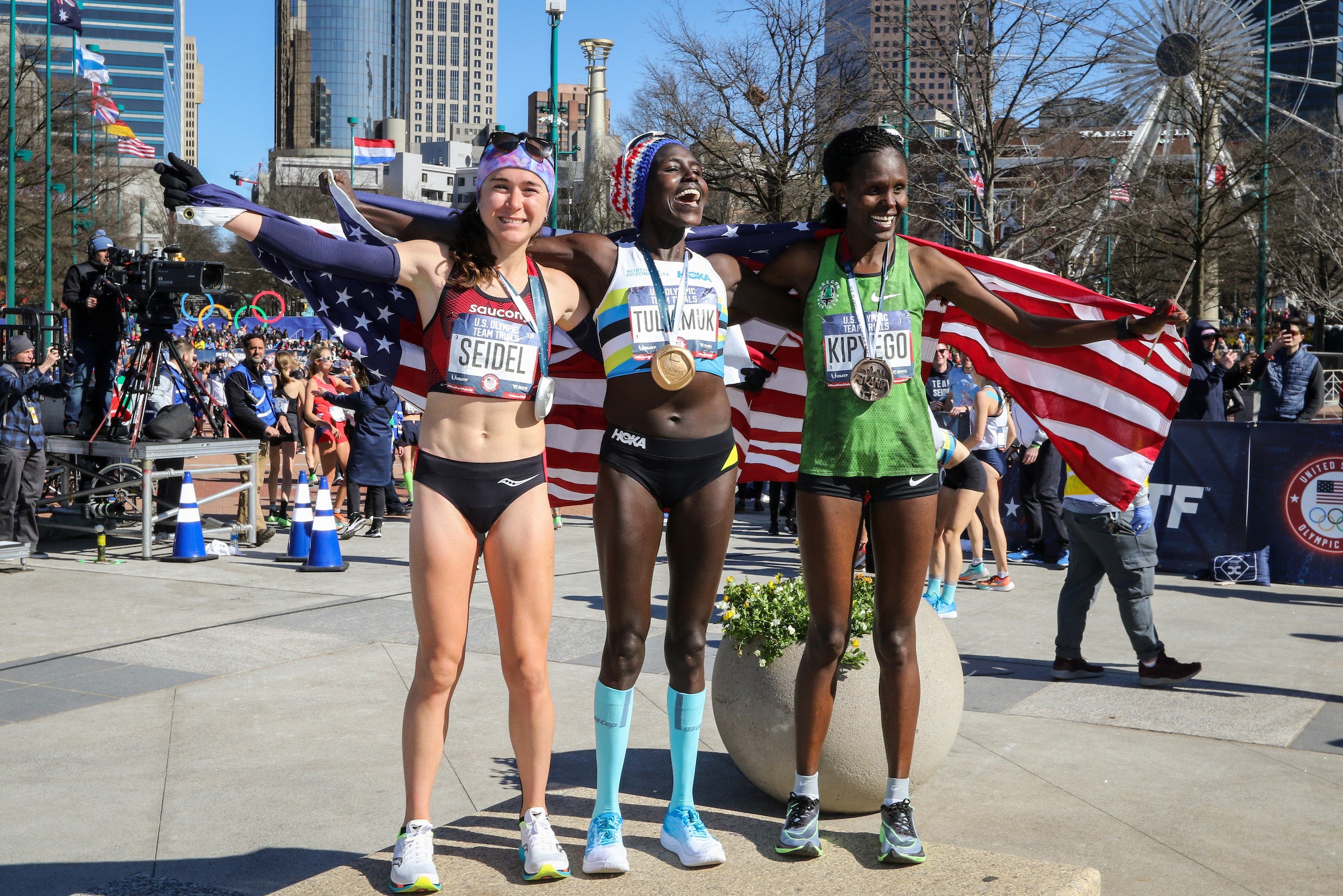 Molly Seidel, Aliphine Tuliamuk, and Sally Kipyego pose with the American flag after winning the Olympic Marathon Trials for the U.S.