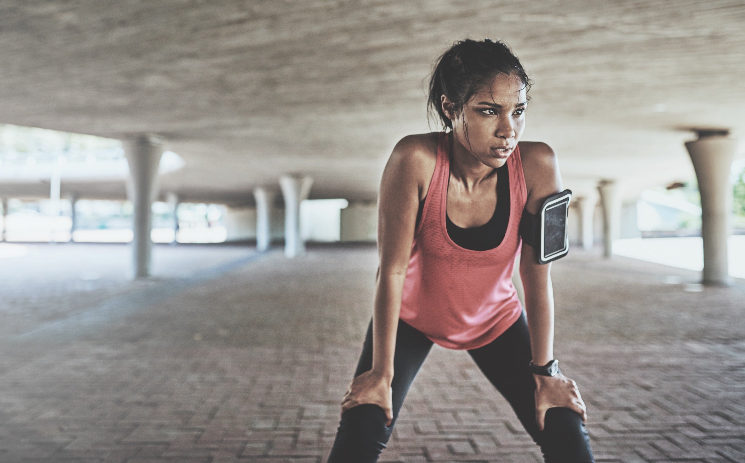 Young woman increasing her heart rate through hard exercises, hands on knees, sweaty