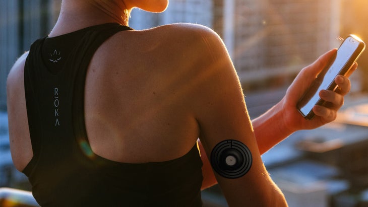 Woman with glucose monitoring sensor checking levels on her phone