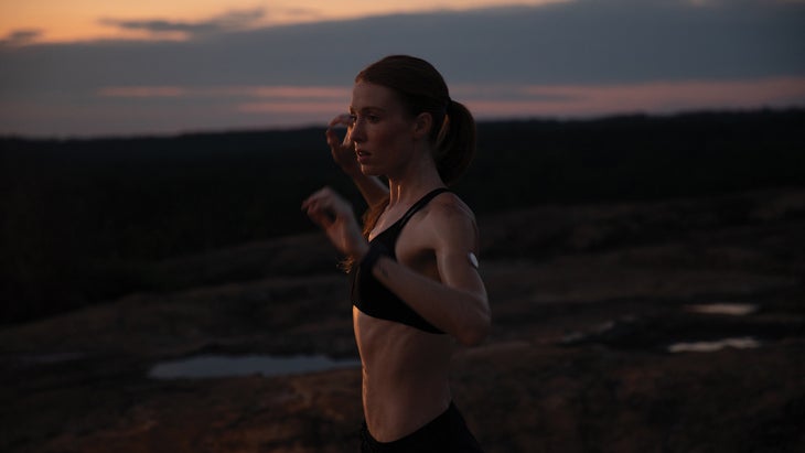 Woman running at sunset with a glucose sensor on her upper arm