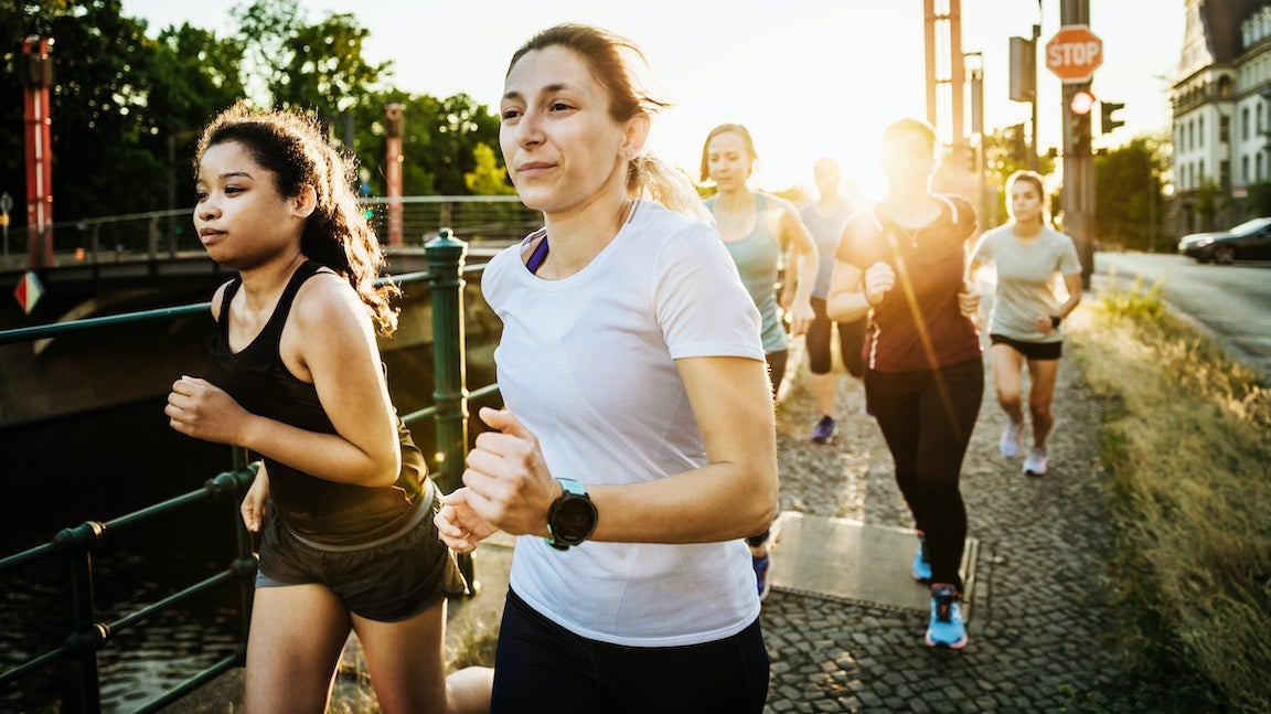 A fitness group for women running together along the canal in the city.