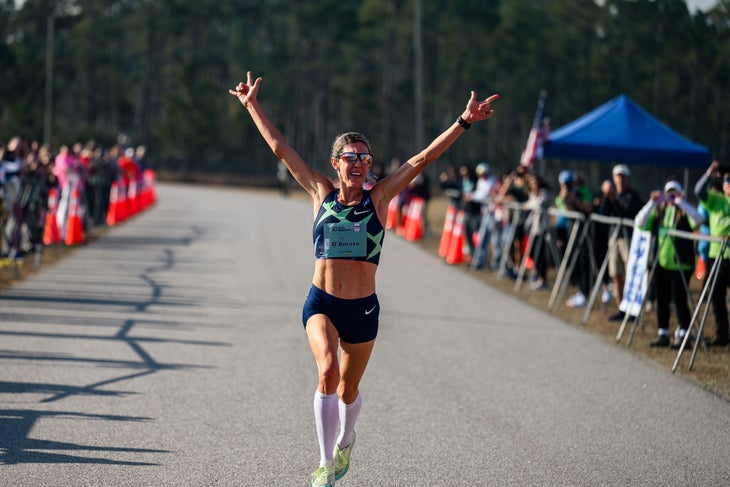 Keira D'Amato crossing the finish line with arms raised as she wins the USATF half marathon championships.