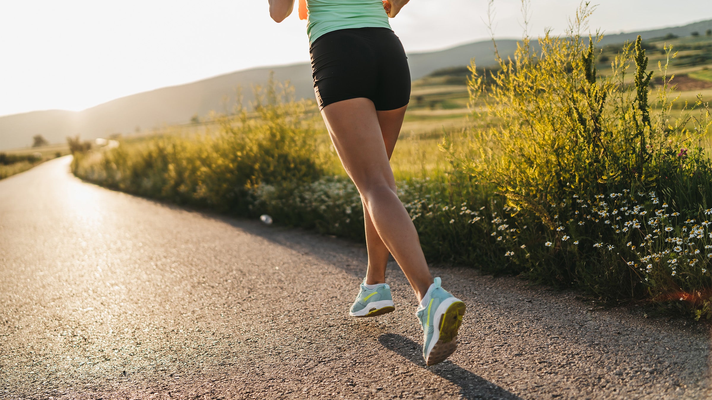 Bottom section of woman running toward sunset