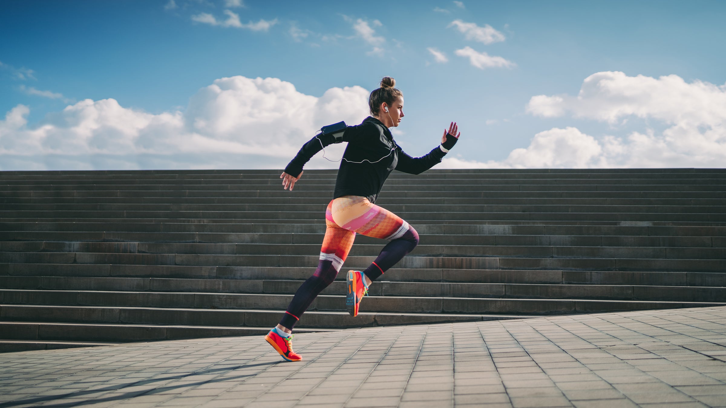 Woman in colorful leggings and shoes sprinting across an empty plaza