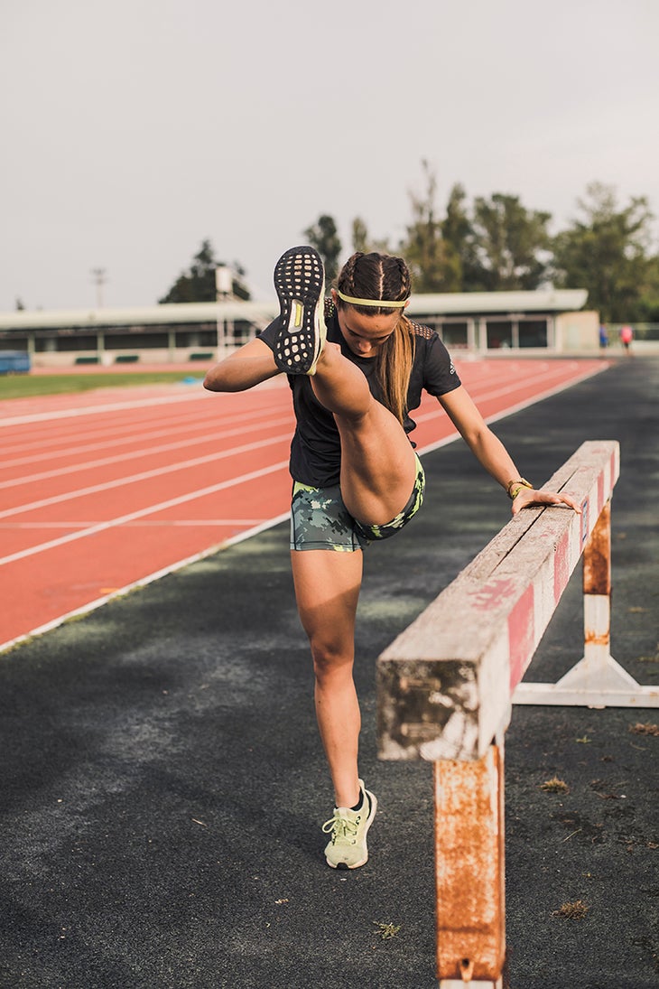 Female athlete doing warm-up exercises on tartan track
