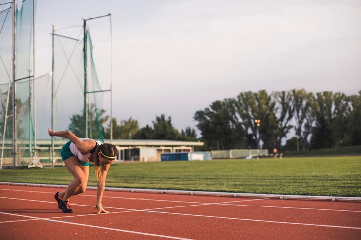 Female runner on tartan track starting a workout