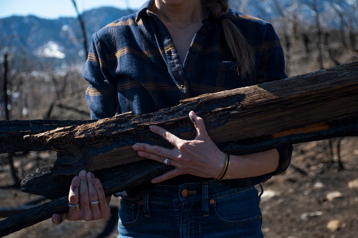 Jenny Simpson holds burned wood from the Marshall wildfire that swept through her property
