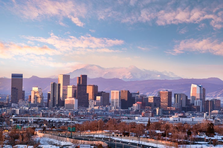 Long-range photo of Denver skyline in front of Rocky Mountains
