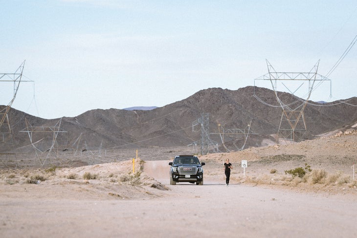 a GMC Denali and a lone runner on a service road in the desert during the speed project