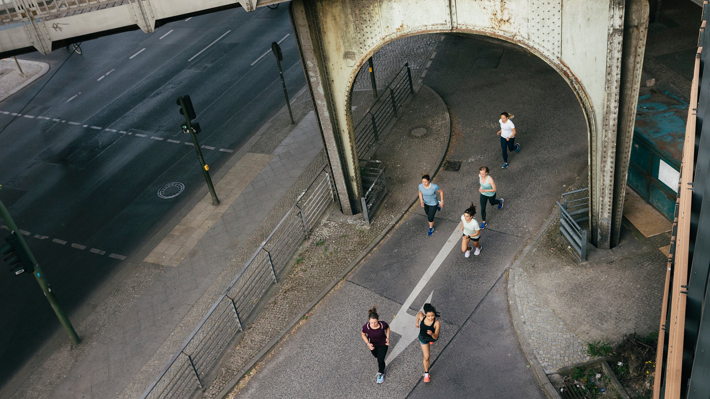 An aerial view of a female fitness group running through the city together.