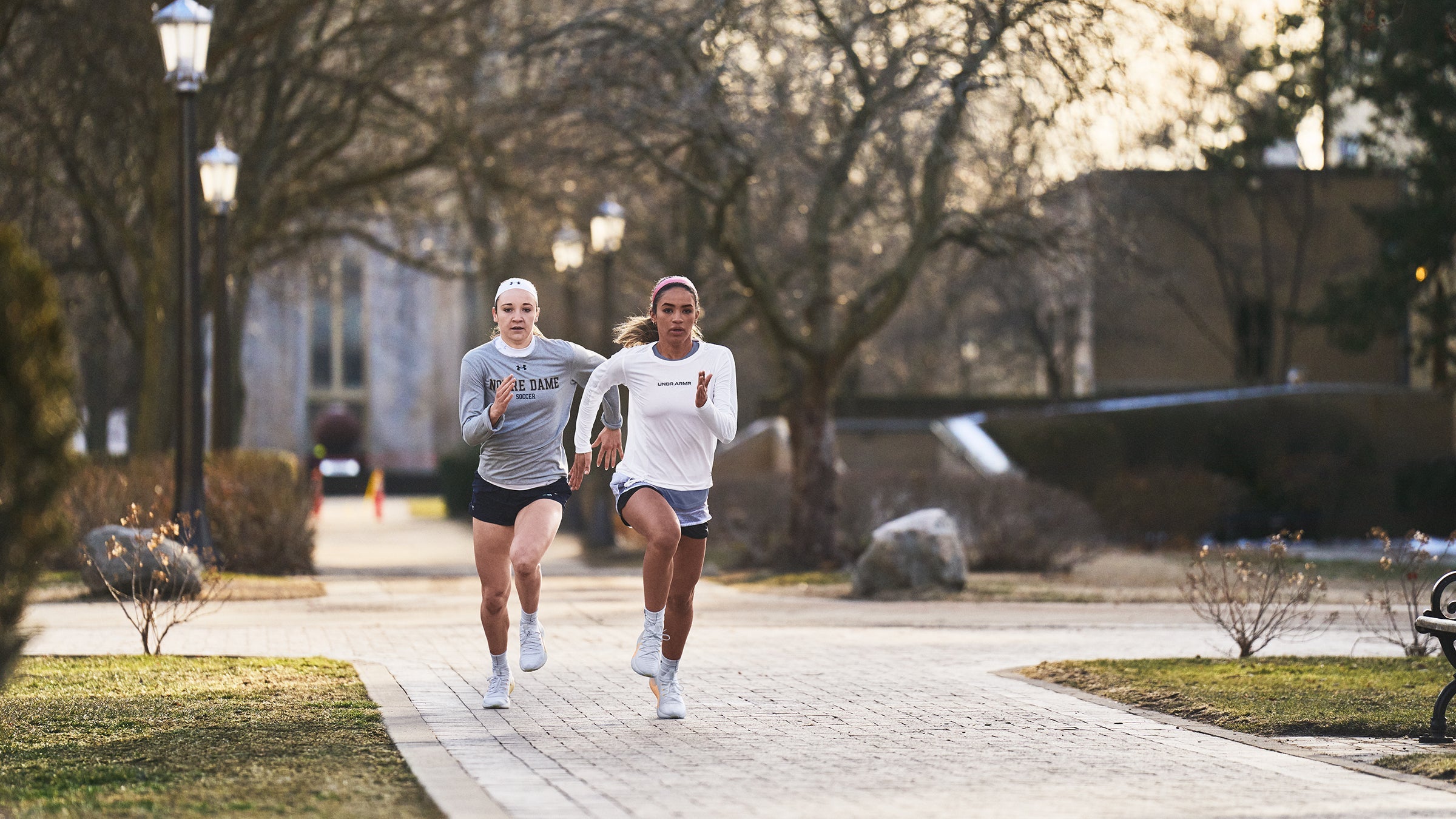 Two women running on a sidewalk.