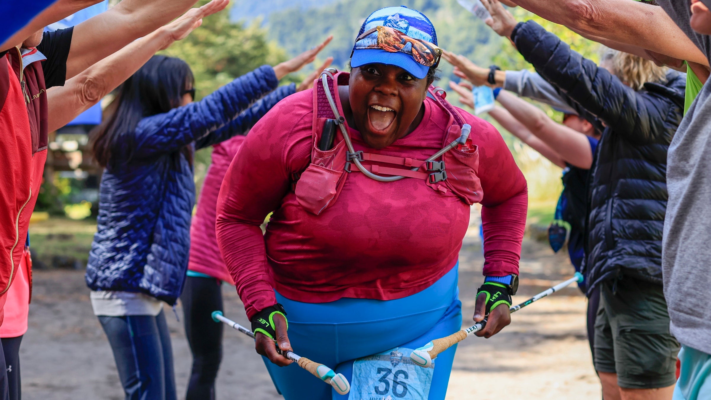 Mirna in a pink shirt running through a tunnel of human arms