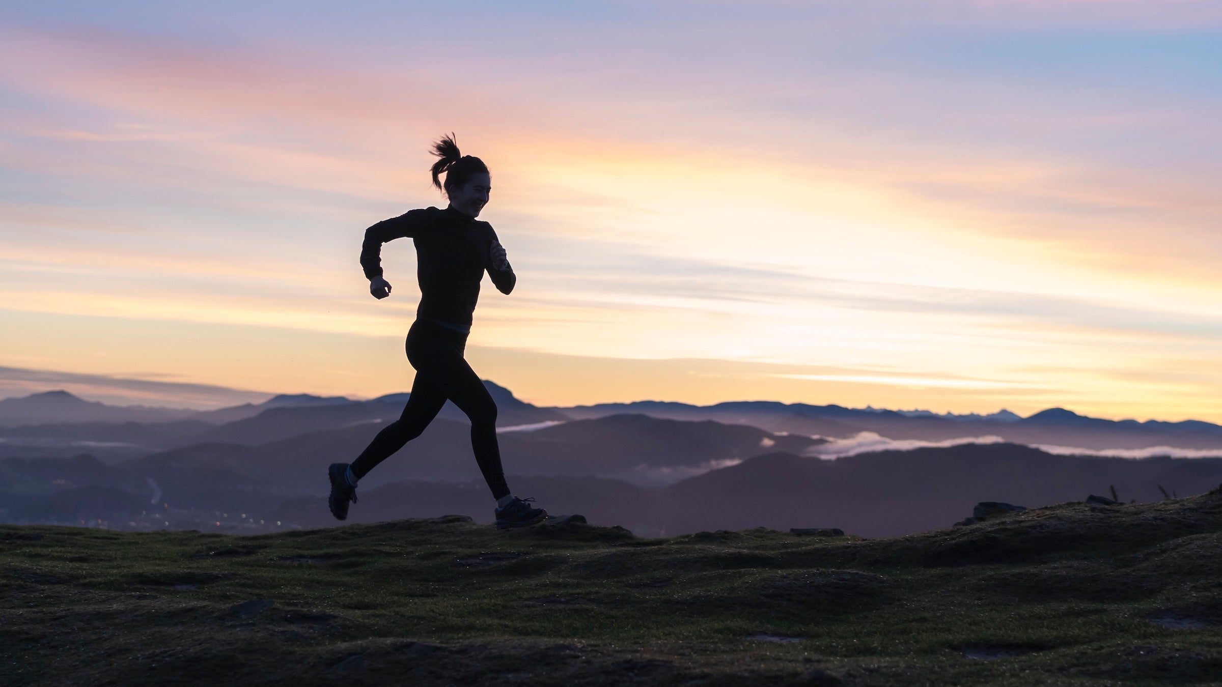 Woman running at sunrise with mountains in the background