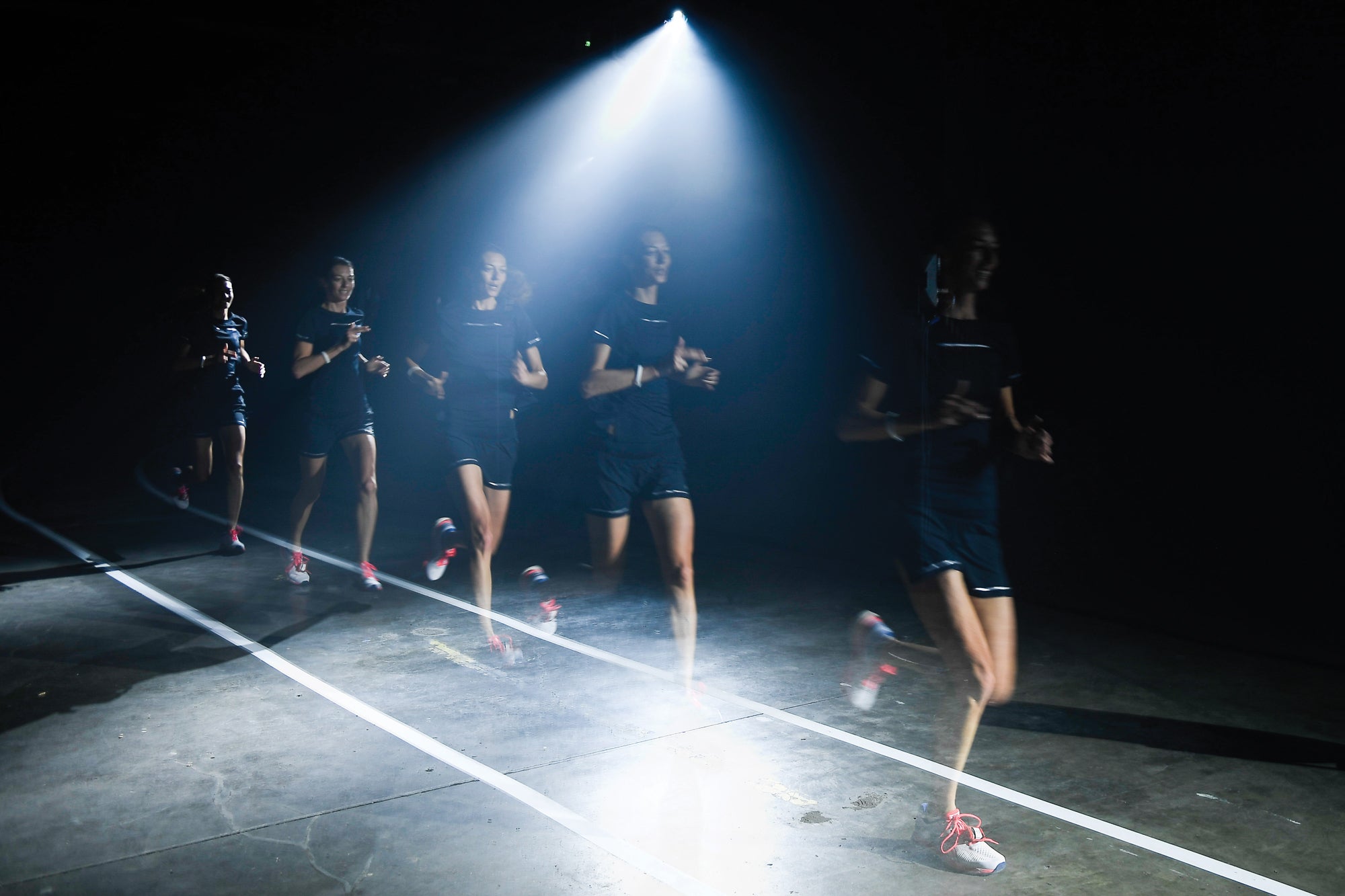 Overlayed images of a woman running on a darkly lit track