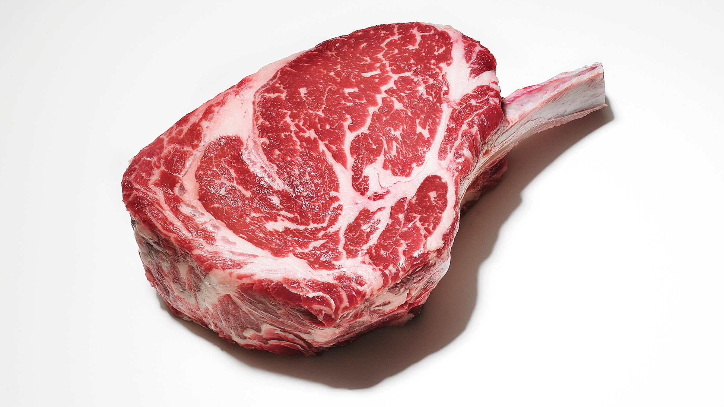 Raw bone-in steak on white background