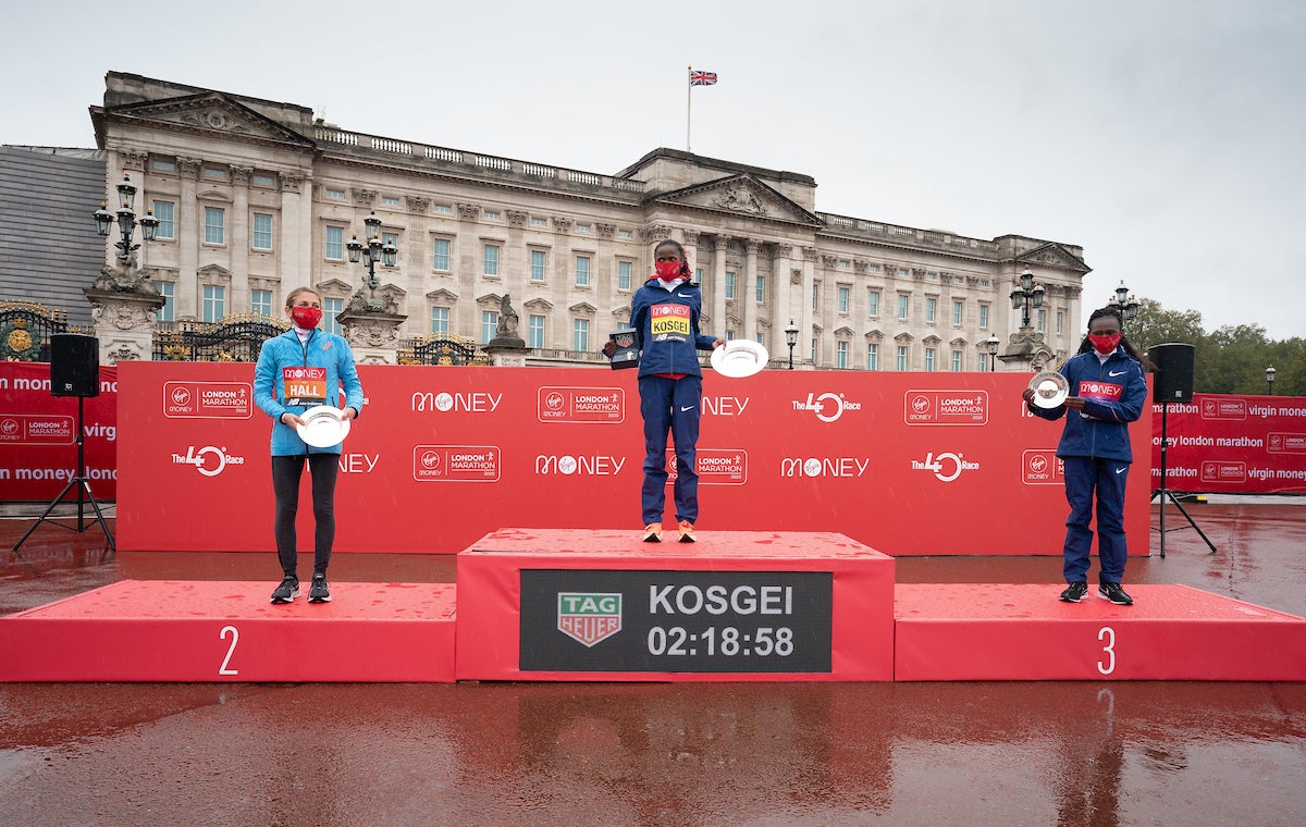 Sara Hall (USA) (left, second place), Brigid Kosgei (KEN) (center, winner) and Ruth Chepngetich (KEN) (right, third place) on the podium outside Buckingham Palace with their trophies for the Elite Women's Race.