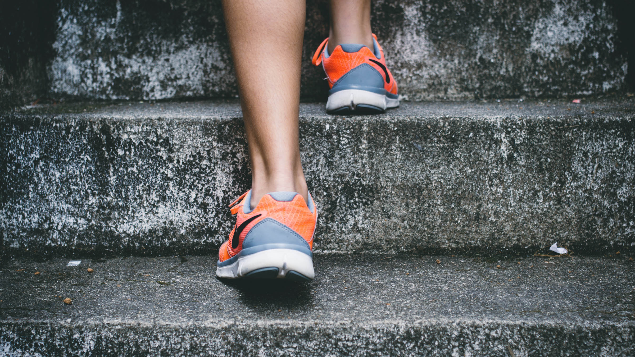 Rear shot of orange Nikes ascending a concrete staircase