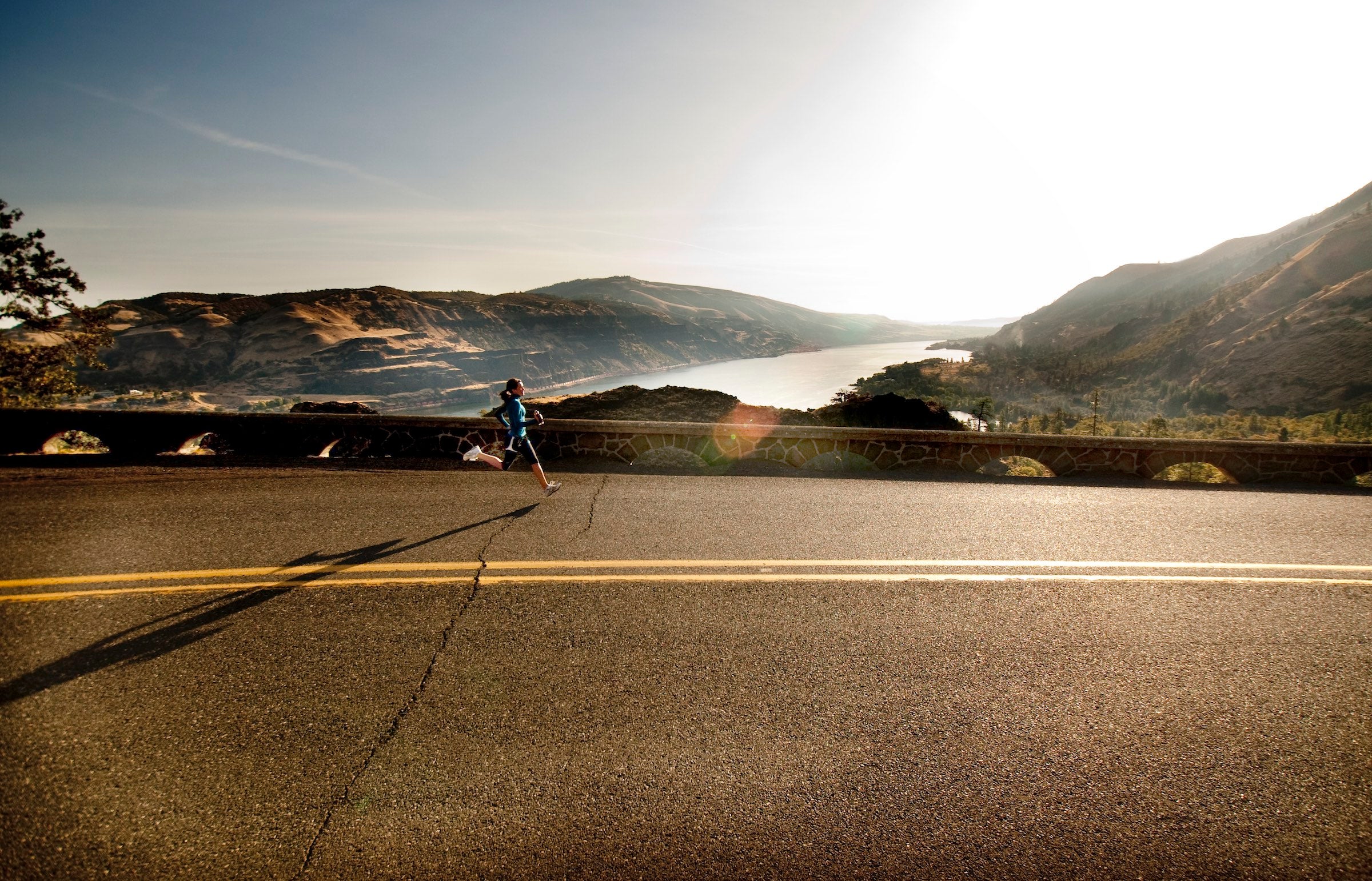 Woman jogging a fartlek workout on highway in landscape