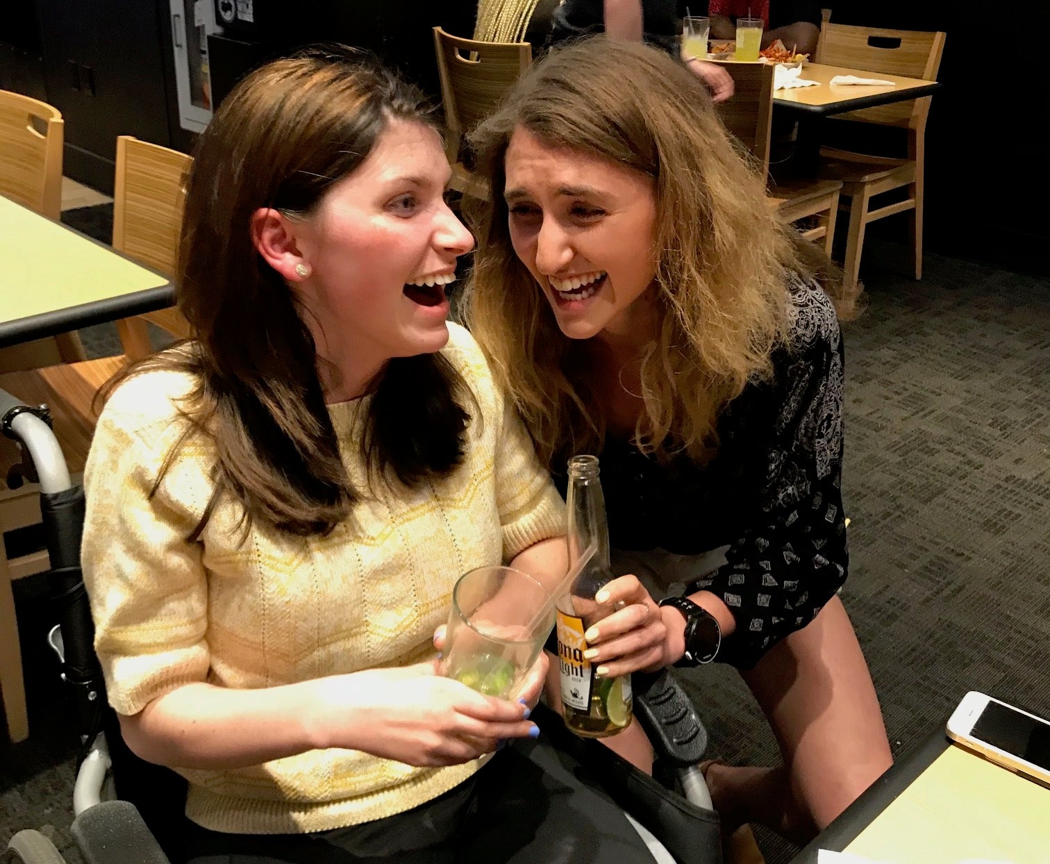 Molly Offstein and sister Maddie smiling and laughing whole holding drinks