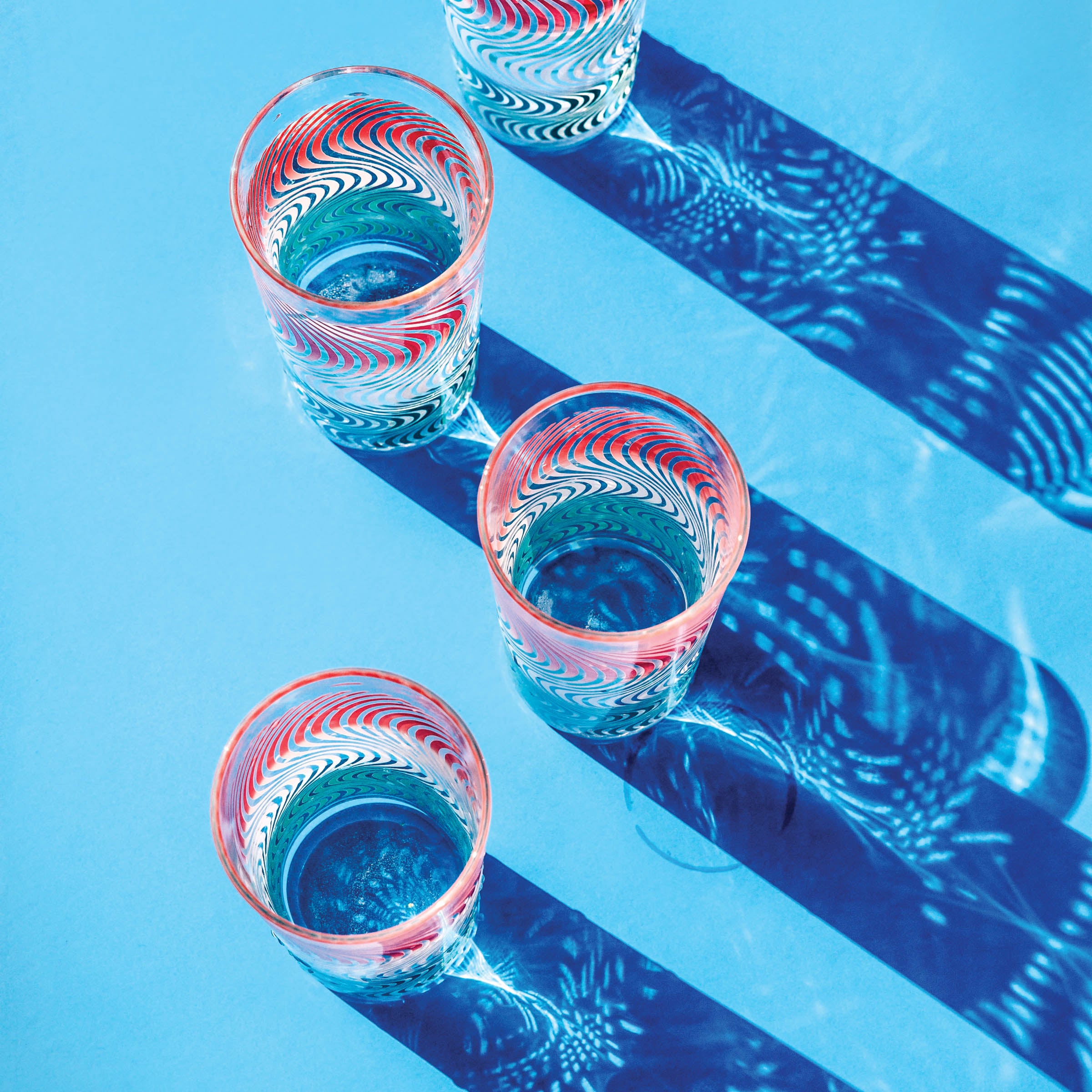 Vintage drinking glasses and their shadows on blue background